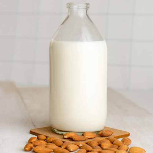 Almond Mylk in a bottle with almonds spread around