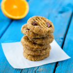 No-Bake Orange Chocolate Chip Cookies stacked on a blue surface with an orange slice in the background