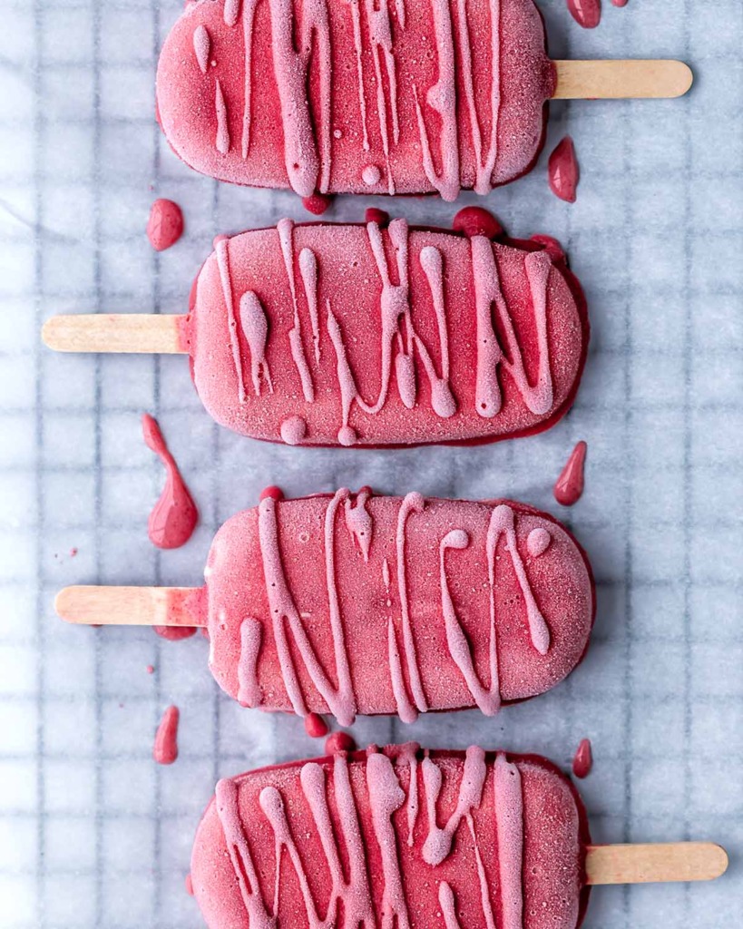 Four Strawberry Cheesecake Popsicles laid on a parchment paper-lined cooling rack
